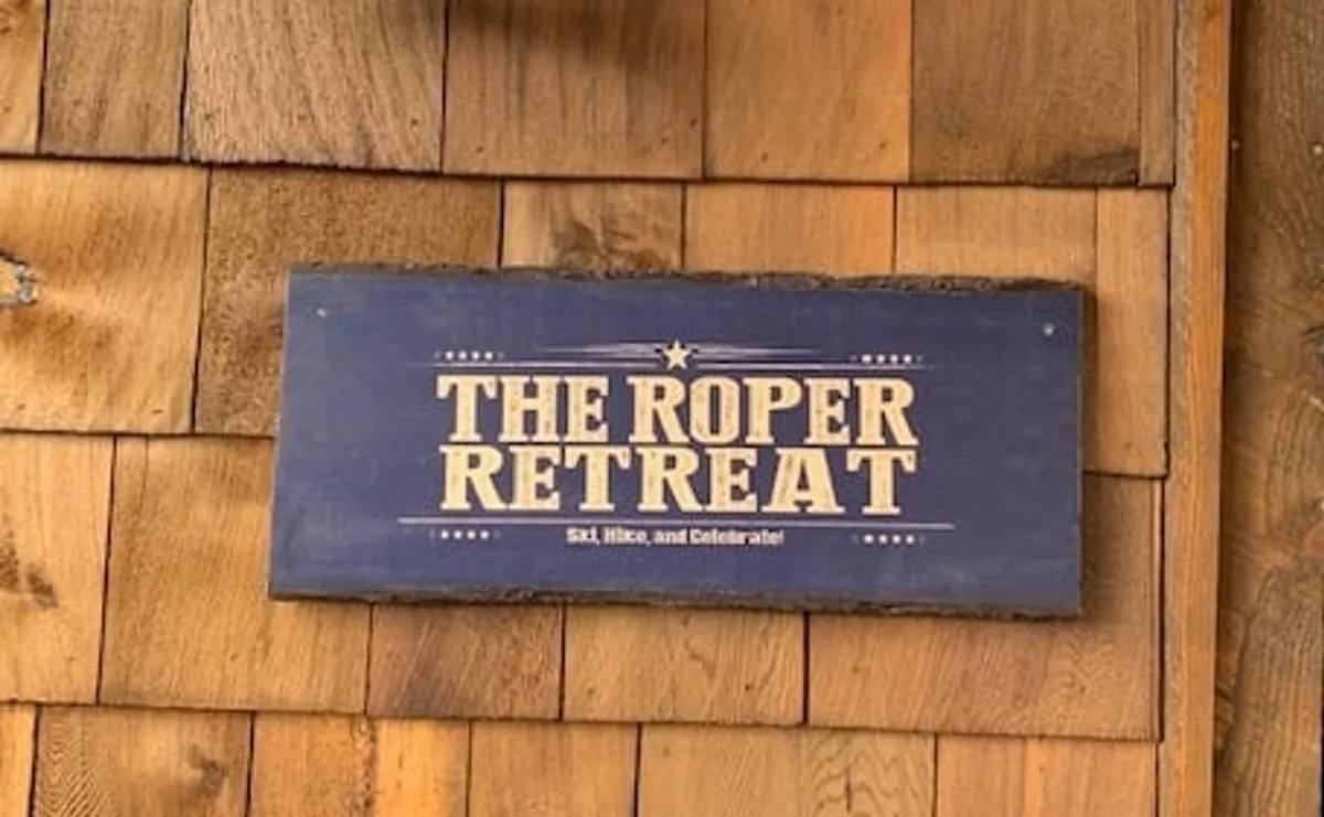 The focal point of this image is 'The Roper Retreat' sign affixed to a wooden wall, hinting at the entrance to the property. The natural textures and signage evoke a sense of arrival and anticipation for adventures and celebrations ahead.